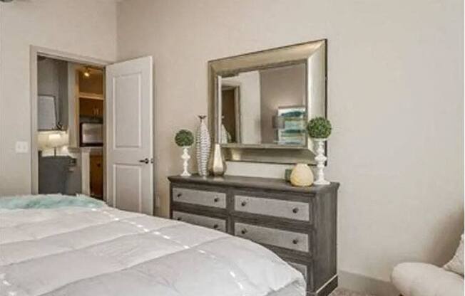 a bedroom with a bed and a dresser with a mirror