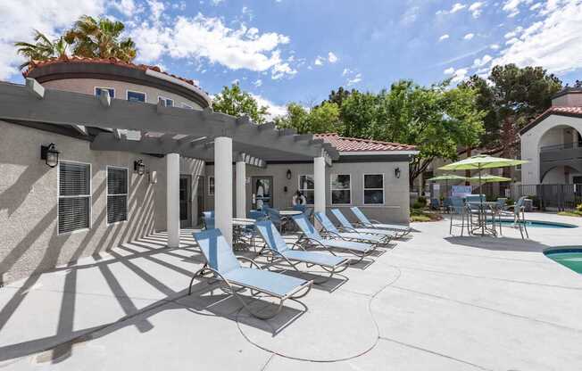 A sunny day at the poolside with chairs and umbrellas.