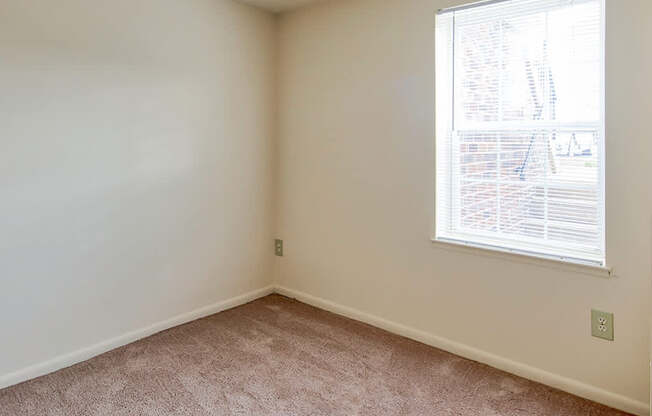 A room with a window and carpeted floor.