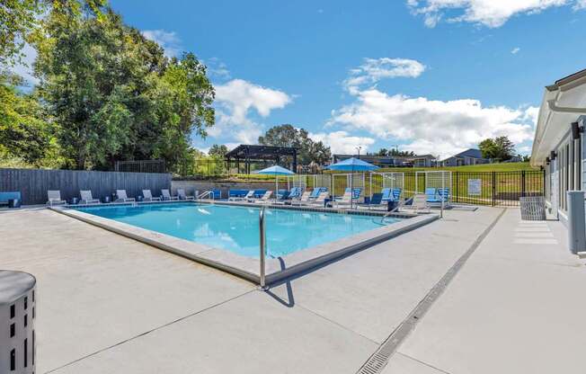 a resort style swimming pool with blue chairs around it at The Lorient Apartments, Pensacola, FL