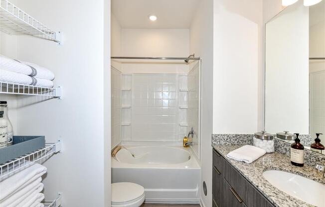 Bathroom with built-in shelves, wide countertop, toilet, and tub/shower at The Station at Brighton apartments for rent