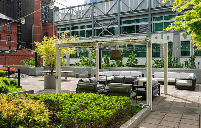 A patio with a white pergola and grey couches.