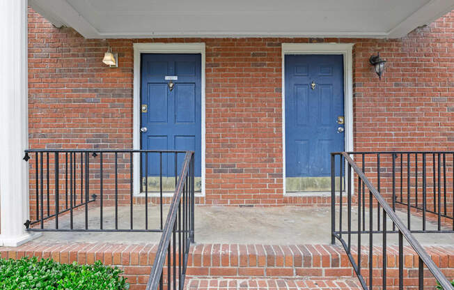 two blue doors on the side of a brick building