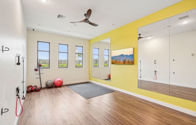 a workout room with a ceiling fan and mirrors on the wall