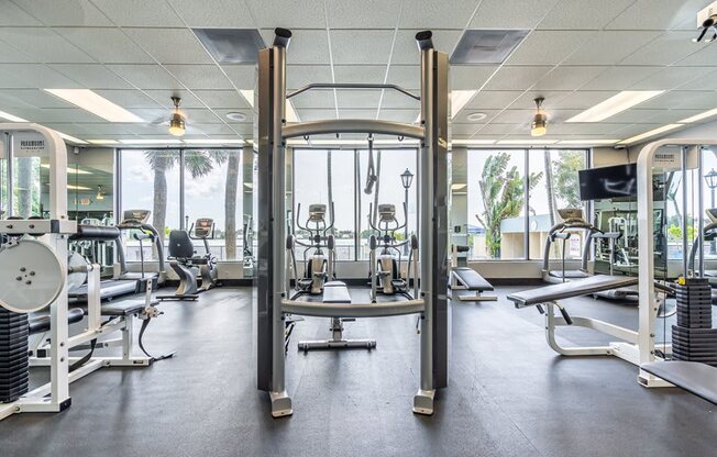 a gym with cardio equipment and windows in the background