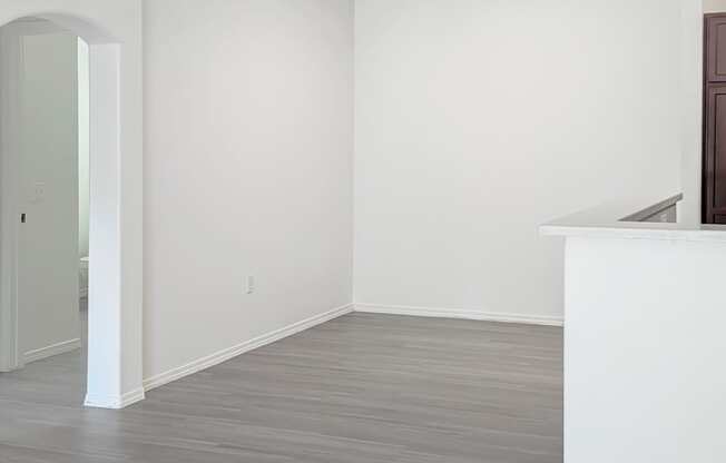 A room with a white wall and a wooden floor.