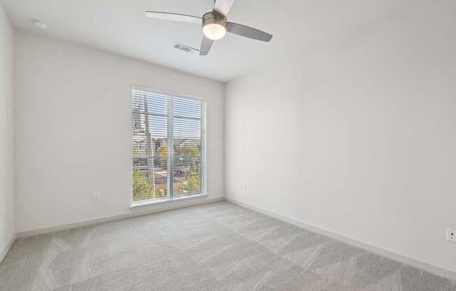 A room with a ceiling fan and carpeted floor.