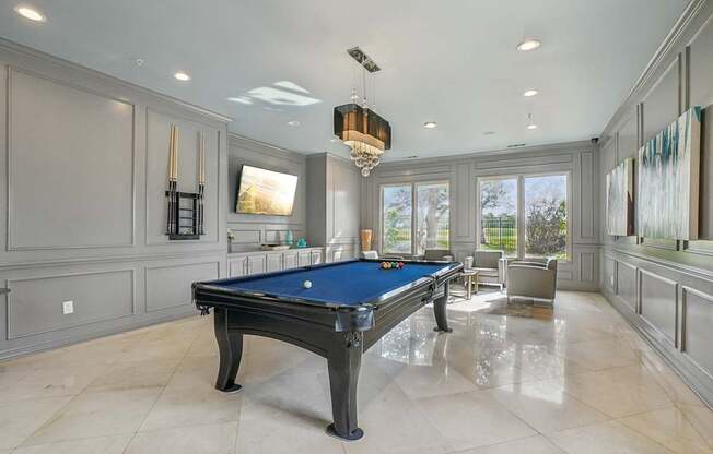 A pool table is in the middle of a room with a light hanging from the ceiling.