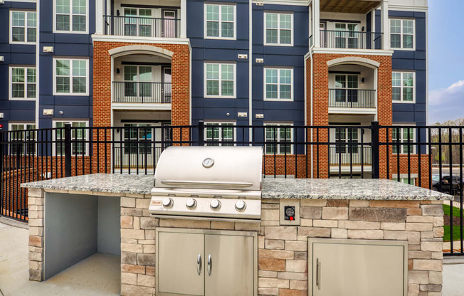 an outdoor kitchen with a stone island with a gas grill at The Bella at Westchester, Midlothian, 23113