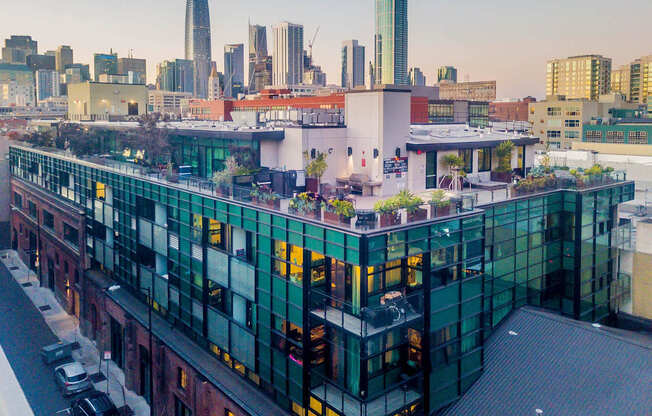 A modern building with green glass windows is in the foreground with a city skyline at Arc Light, California, 94107