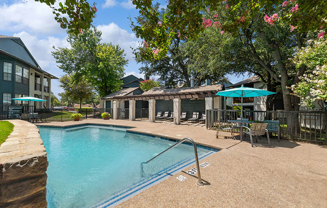 Community Swimming Pool with Pool Furniture at Bridges at Deer Run Apartments in Dallas, TX.