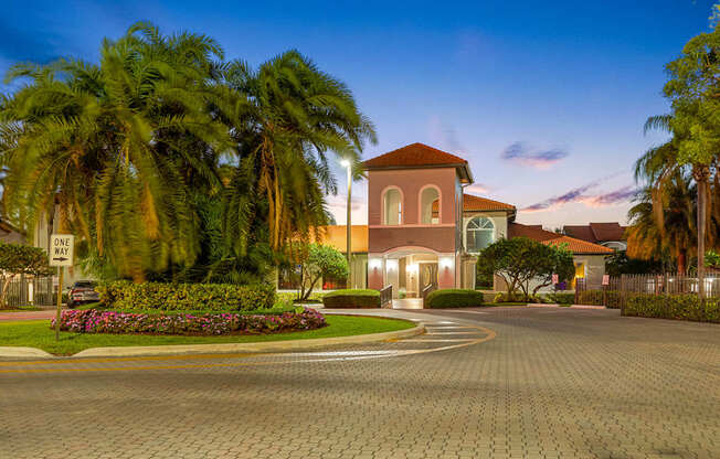 A house with a driveway and palm trees in front.