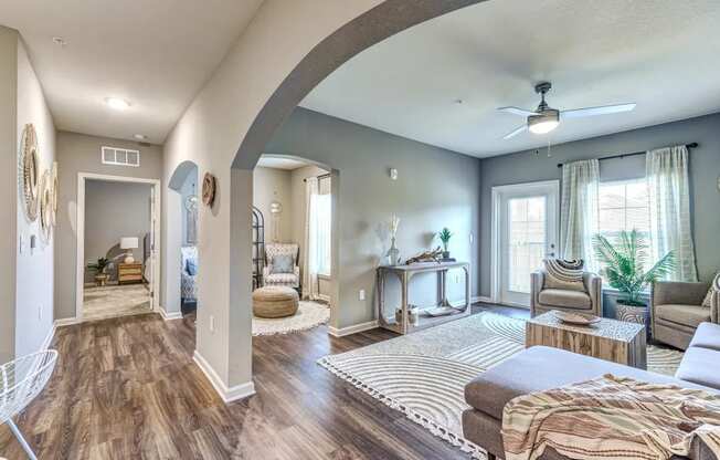 Living room and hallway with a couch, chair, coffee table and two windows at Flats at Sundown apartments in North Port, Fl