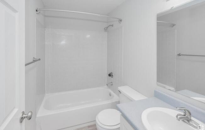 A white bathroom with a toilet, sink, and bathtub.