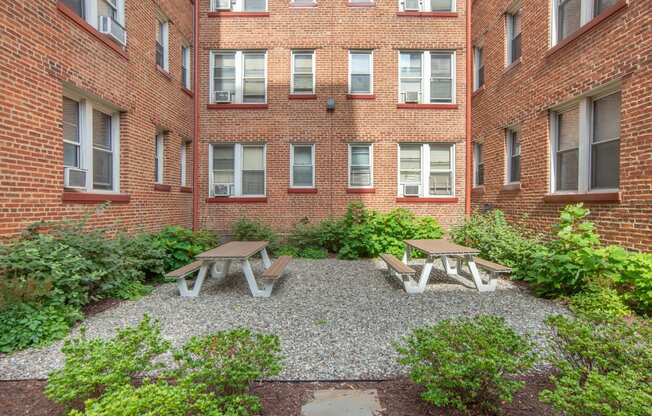 a courtyard with two picnic tables in front of a brick building