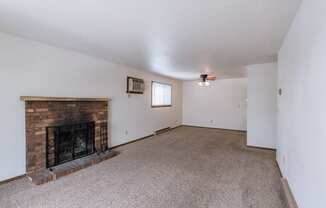 a living room with a brick fireplace and a carpeted floor. Fargo, ND Plumtree Apartments