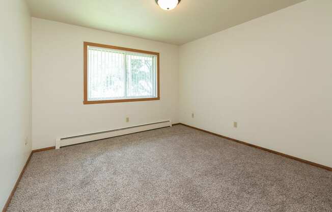 a bedroom with carpet and a window. Fargo, ND Islander Apartments