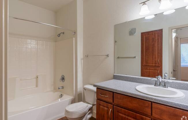 A bathroom with a white tub, sink, and toilet.