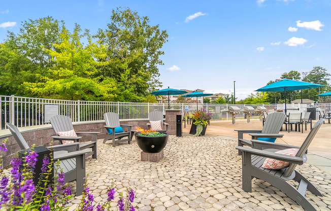 an outdoor patio with tables chairs and umbrellas and a fire pit