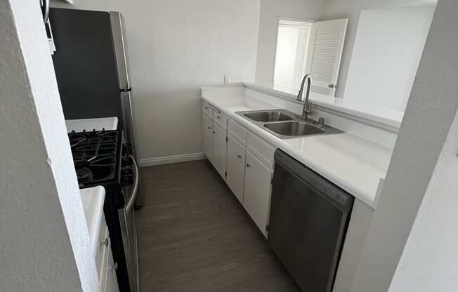 Kitchen with Hardwood Floors, White Cabinets and Stainless Steel Appliances