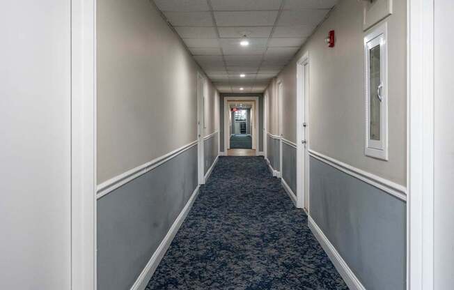 A long hallway with a carpeted floor and white walls.