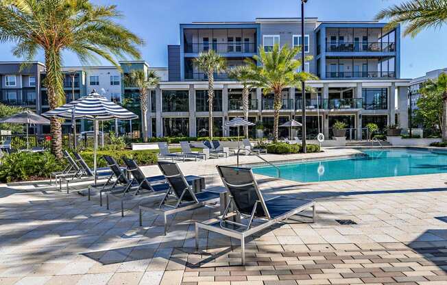 a swimming pool with chairs and umbrellas in front of a building