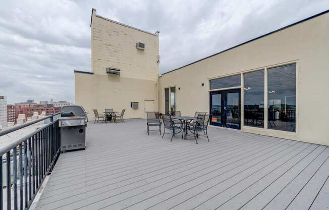 the deck of a building with a table and chairs and a grill