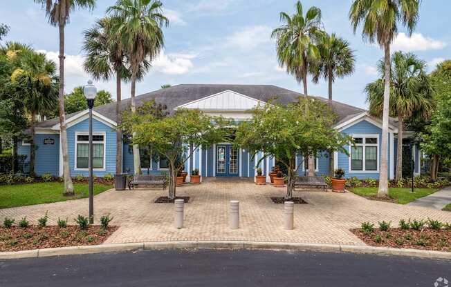 A blue building with a white roof is surrounded by palm trees.