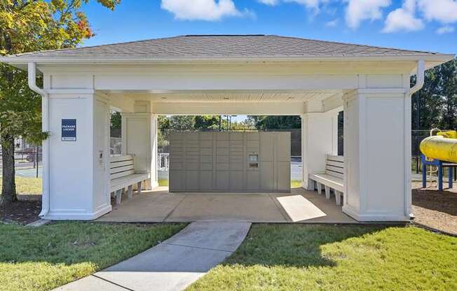 A white pavilion with a brown roof and a yellow object in the background.