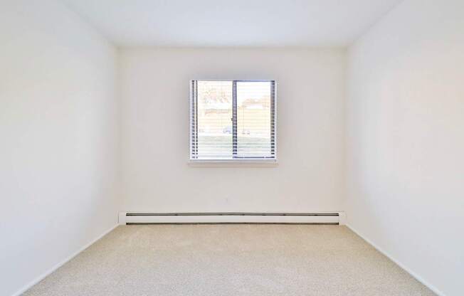 a spacious room with white walls and a window