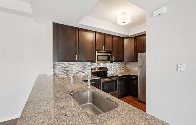 A kitchen with a granite countertop and stainless steel appliances.