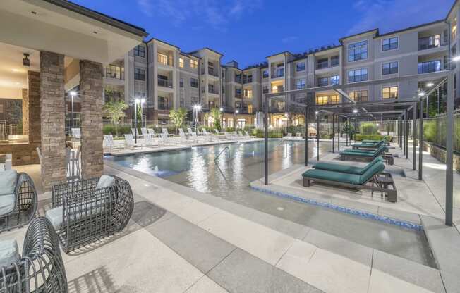 a swimming pool with lounge chairs in front of an apartment building at The Hendrix, Georgia, 30329