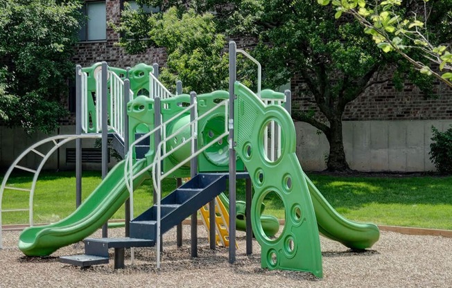 a childrens playground with a green slide