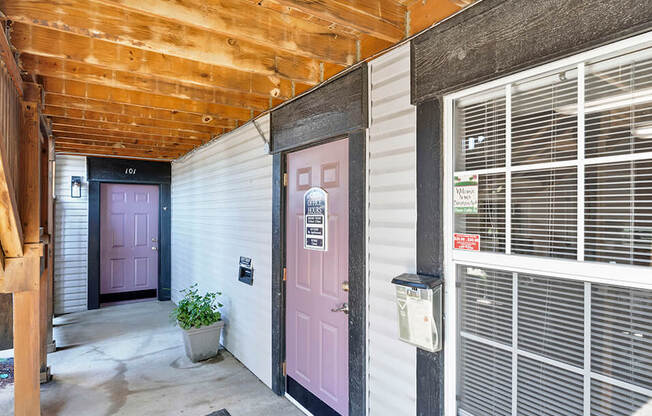 a pink door at the entrance to a white building with a wooden ceiling