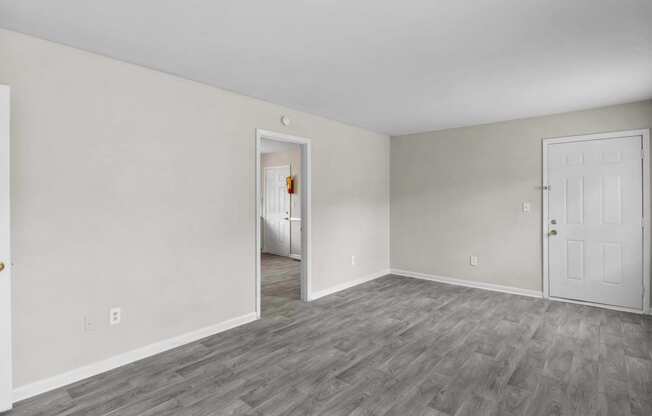 the living room of an apartment with white walls and wood flooring