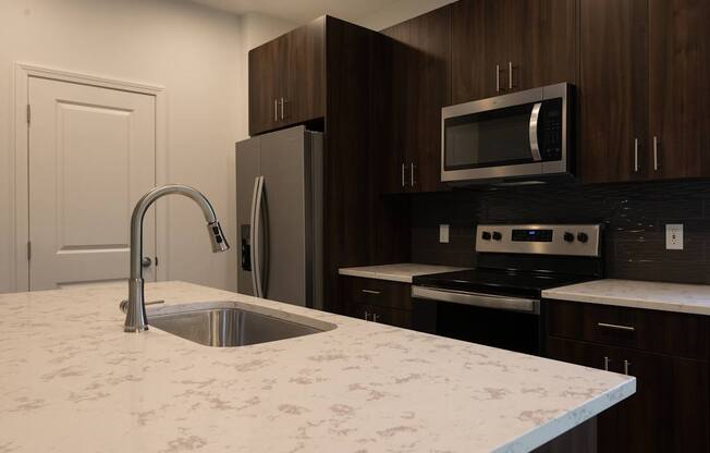 a kitchen with a marble counter top and a sink at The Clearing at ONE28, Olathe, 66062