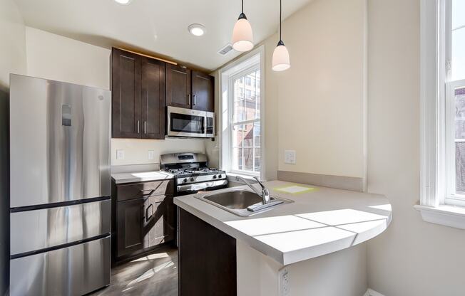 kitchen with espresso cabinetry, breakfast bar and stainless steel appliances at petworth station apartments in washington dc