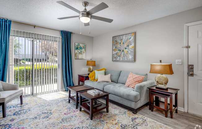 A living room with a grey couch, a rug, and a ceiling fan.