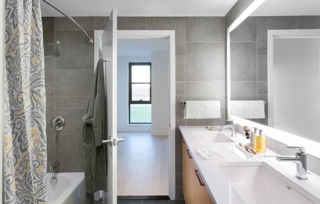 Luxurious double-sink bathrooms with sleek tile surround and backlit mirros