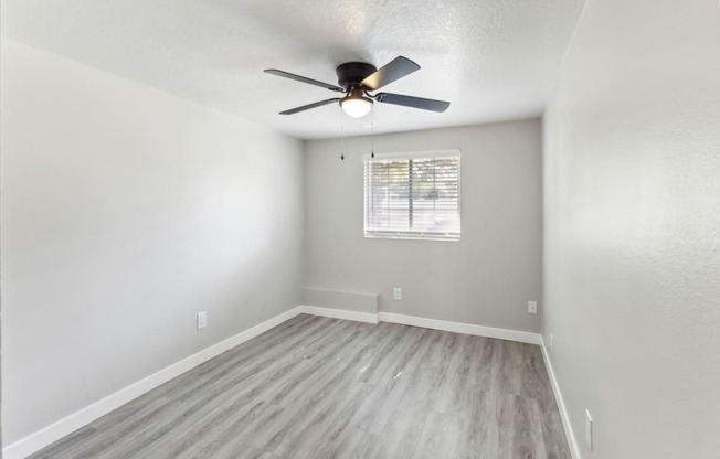 an empty living room with a ceiling fan and a window