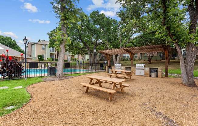 a picnic area with benches next to a swimming pool