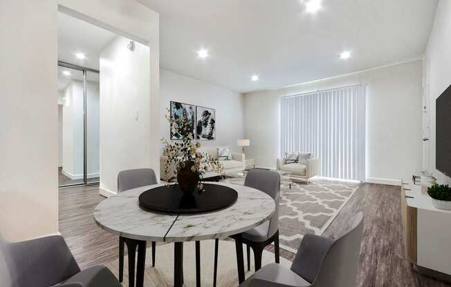 A modern dining room with a round marble table and grey chairs.