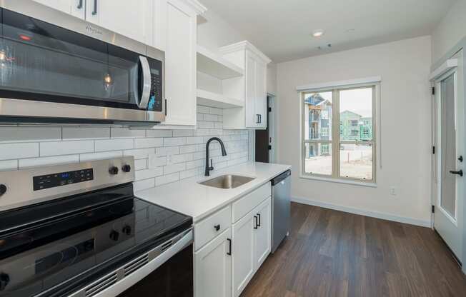 a kitchen with white cabinets and black appliances and a window at The Crossings at Windsong, Arizona