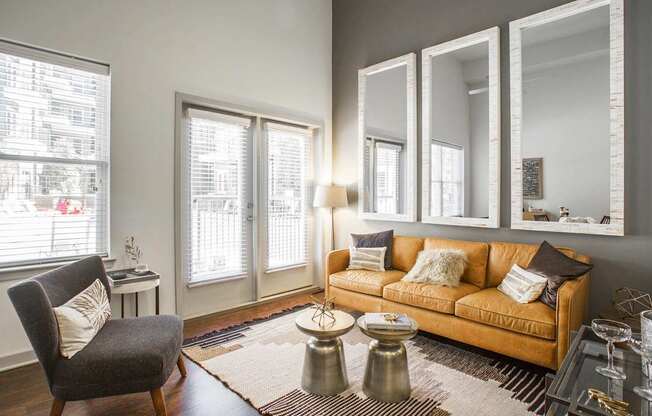 A living room with a couch, chair, and mirrors.