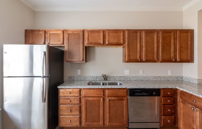 an empty kitchen with wooden cabinets and a stainless steel refrigerator