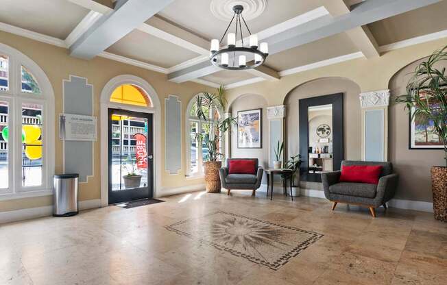 A spacious lobby with a chandelier, sofas, and a large rug at the Brookmore Apartments leasing office.