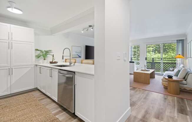 a kitchen with a sink and a dishwasher and a living room with a couch