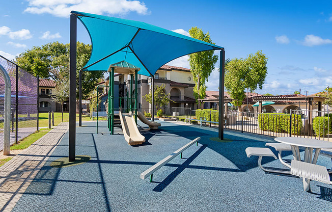 Community Playground with Slide and Blue Canopy at Stillwater Apartments in Glendale, AZ.