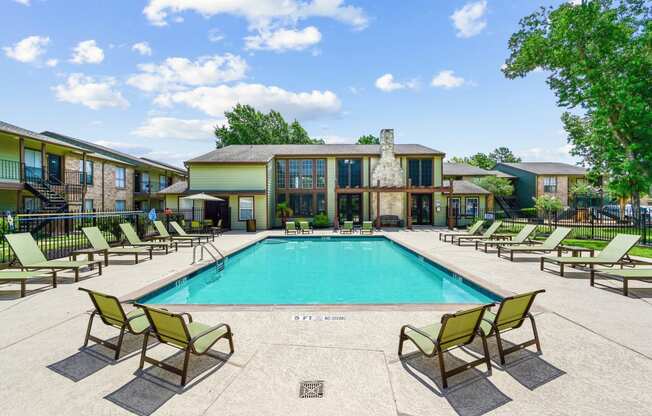 a swimming pool with chaise lounge chairs and a building in the background