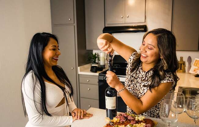 a woman pouring a bottle of wine into another woman